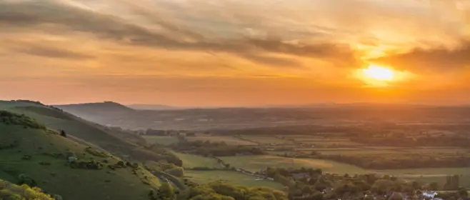 Sunset over lush countryside landscape.