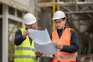 2 people looking at plans witrh hard hats to provide supported housing