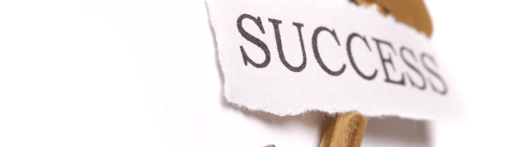 A key with a small strip of paper that has the word SUCCESS on it.