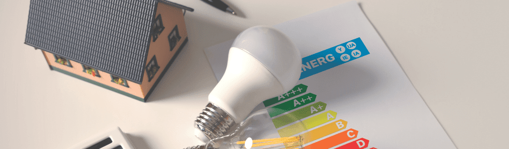 A table with various props on it. A small model home, two light bulbs and an EPC rating card.