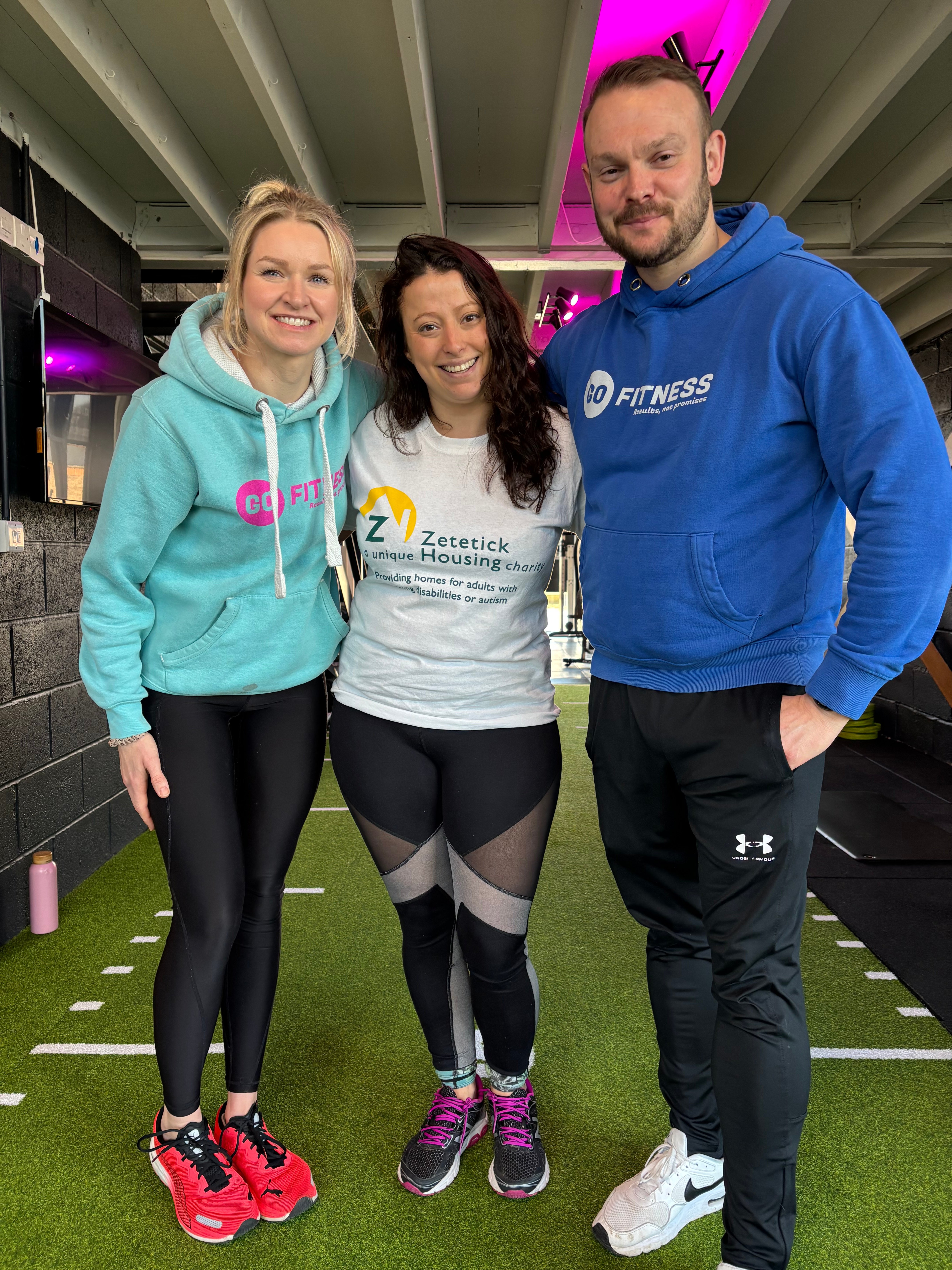 Three people smiling in a gym setting.